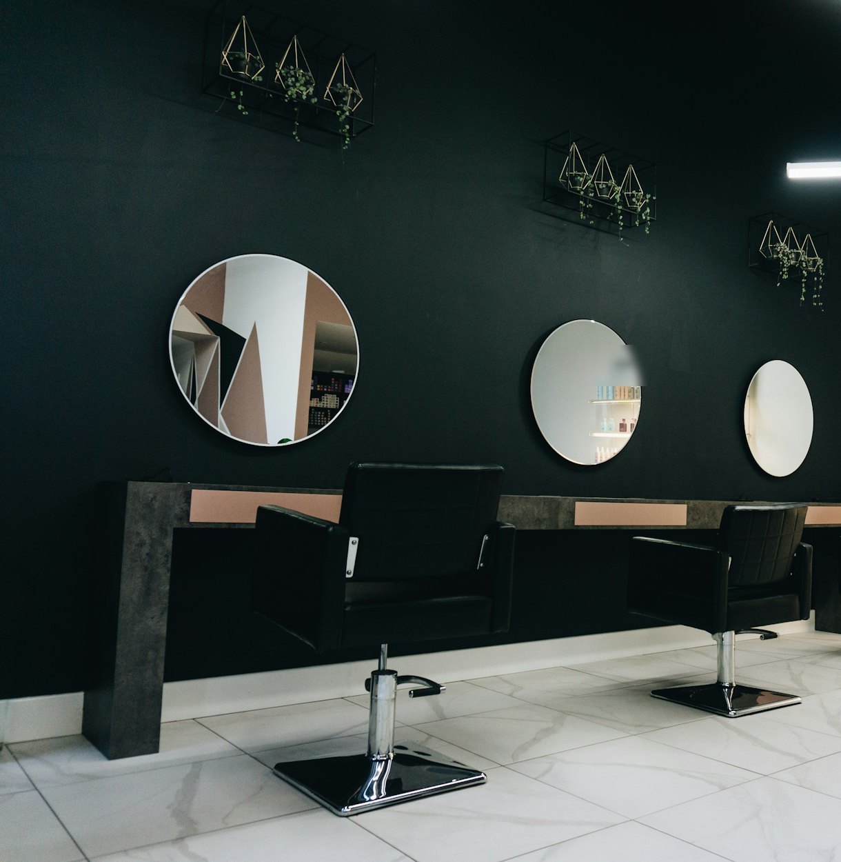 Hair salon interior with black styling chairs facing round mirrors