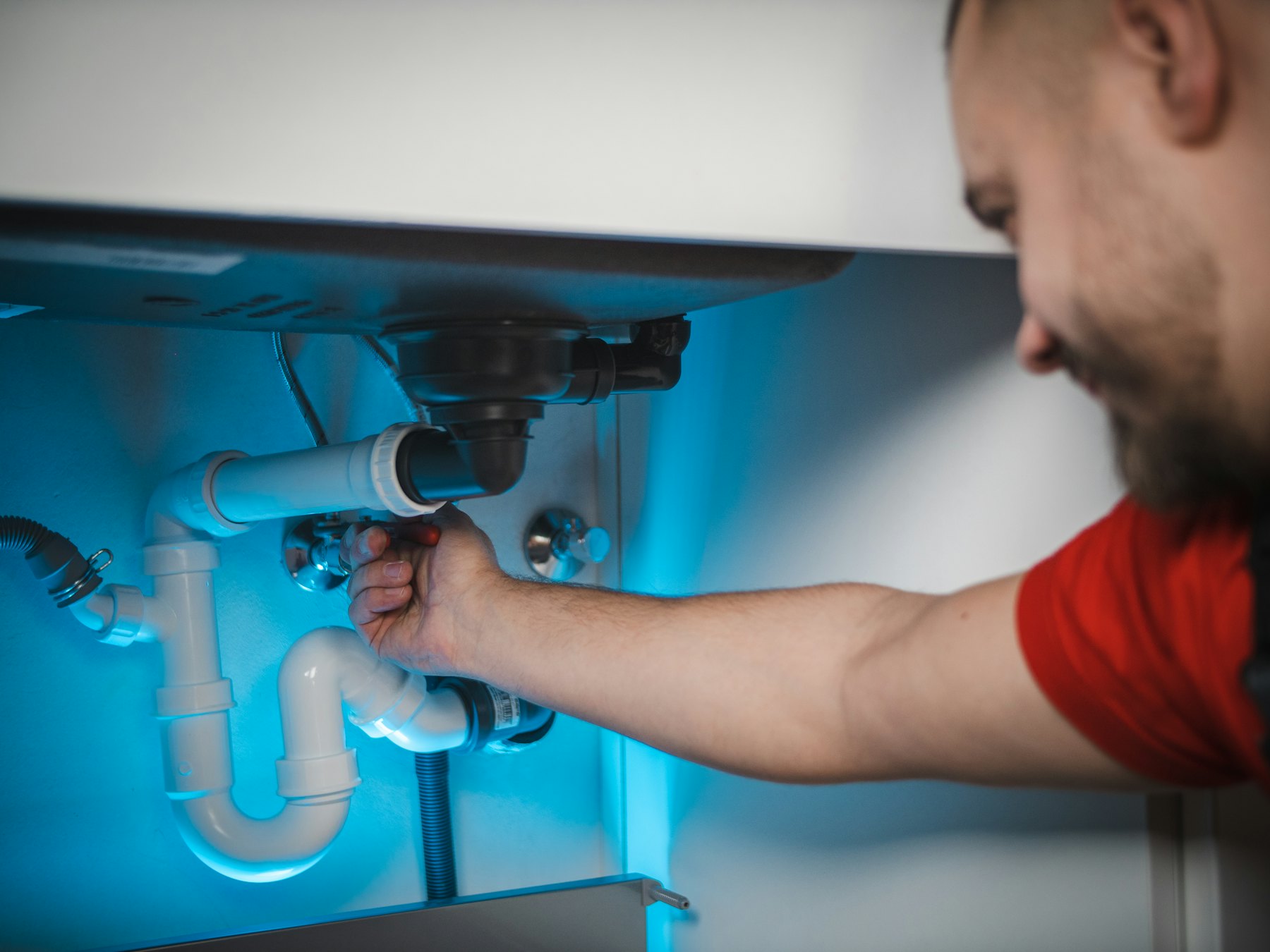 Plumber repairing the pipes under a kitchen sink